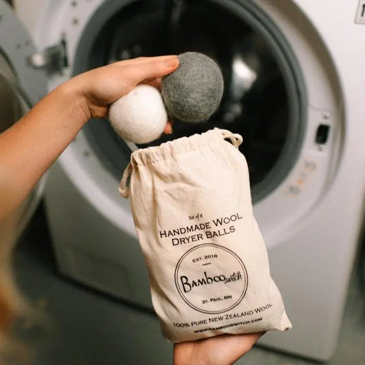 Handmade wool dryer balls from Bamboo Switch with a bag in front of a washing machine.
