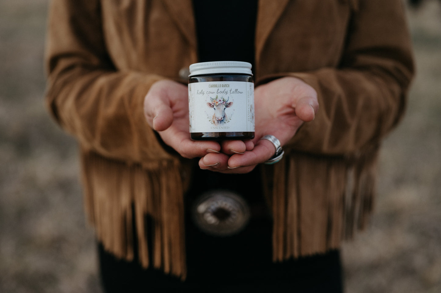 Famer holding a jar of tallow with a blurred background