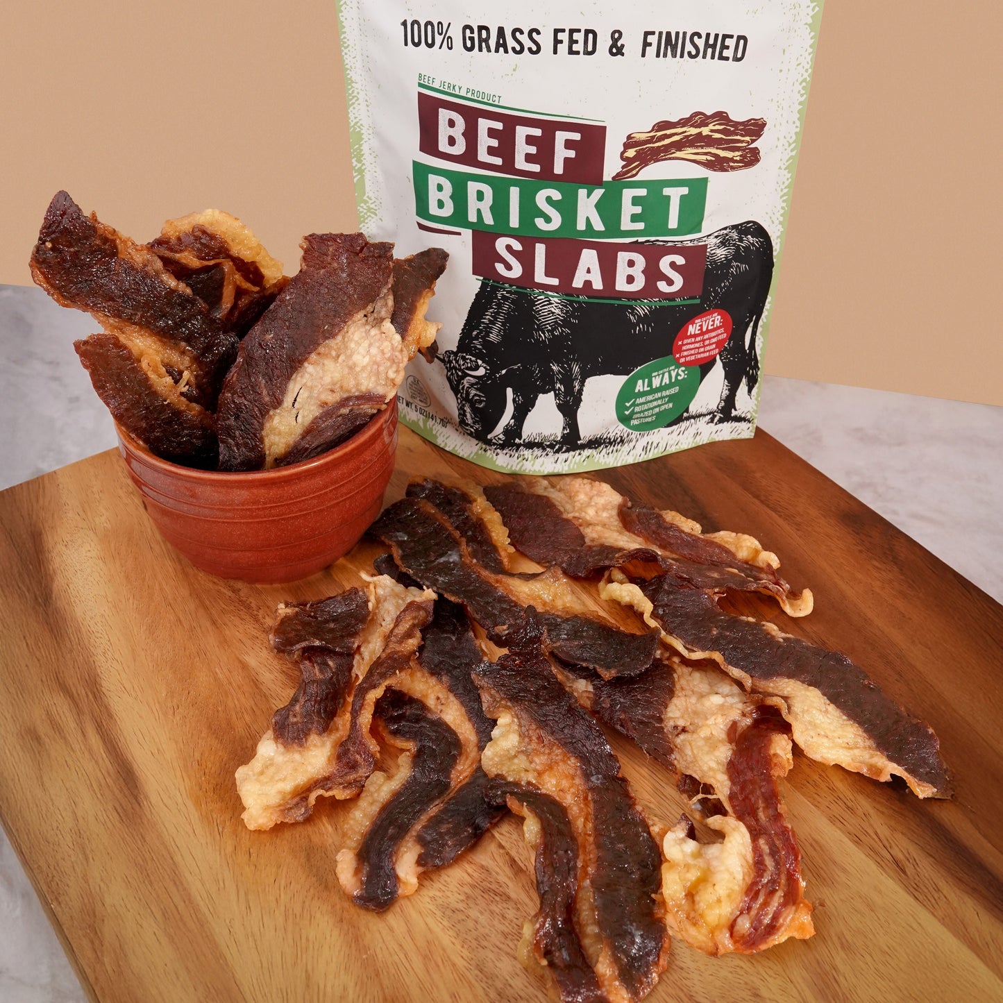Grazly beef brisket slabs on a wooden cutting board with a package labeled 'Beef Brisket Slabs' in the background.